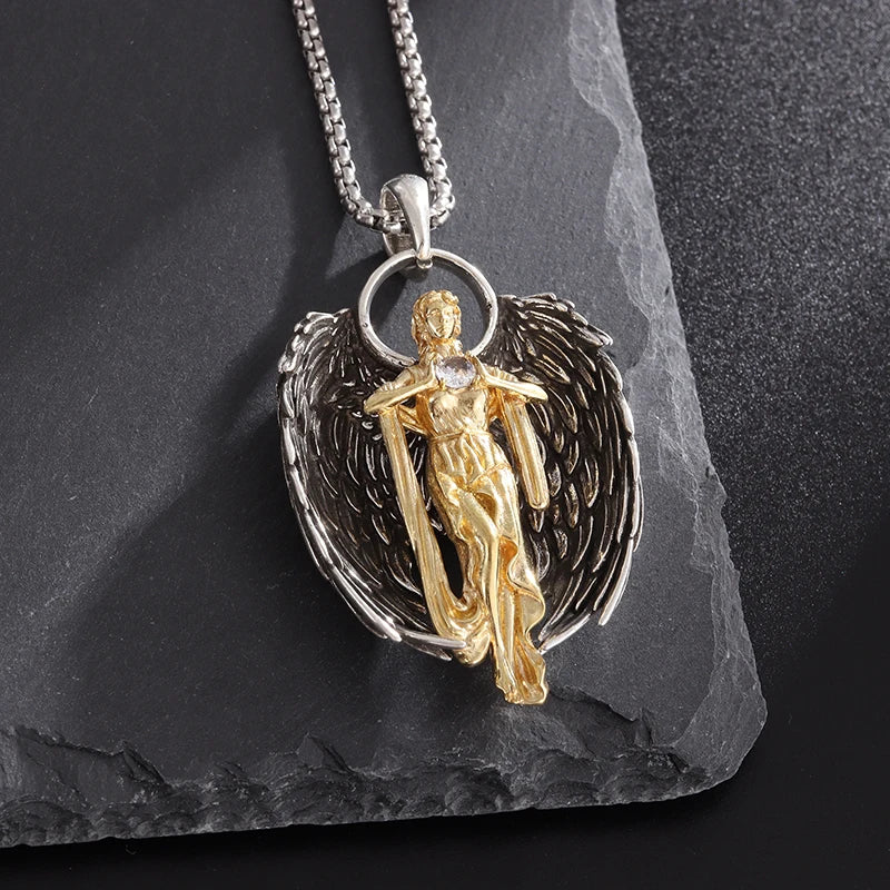 Gold and silver angel pendant on a dark stone surface