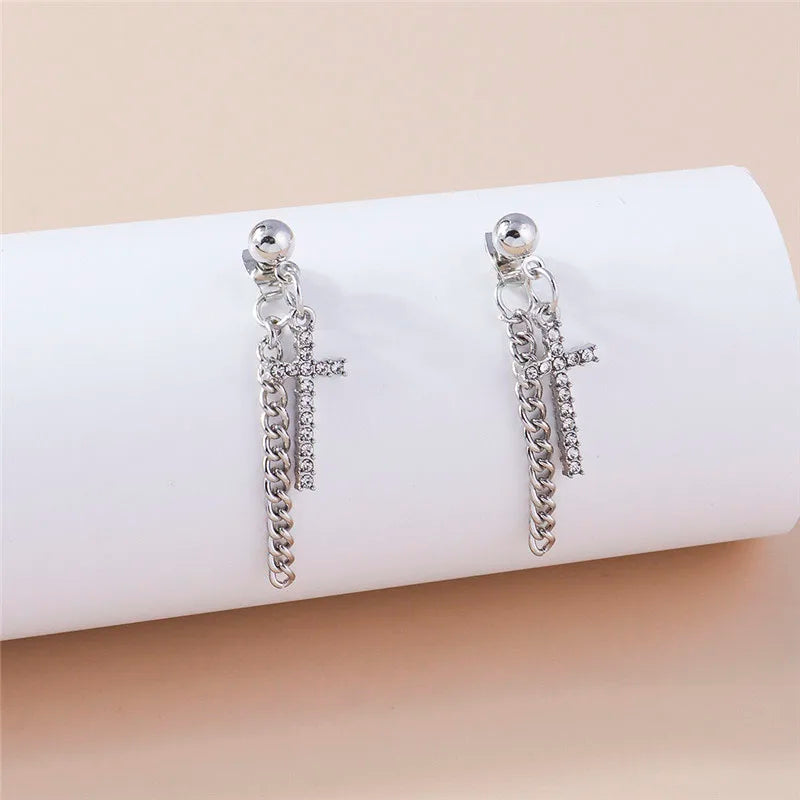Silver cross earrings with chain details on a white roll of paper.