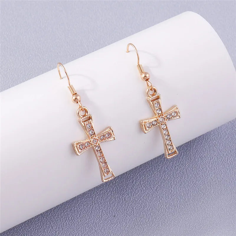 Rose gold cross earrings with clear stones on a white and gray background