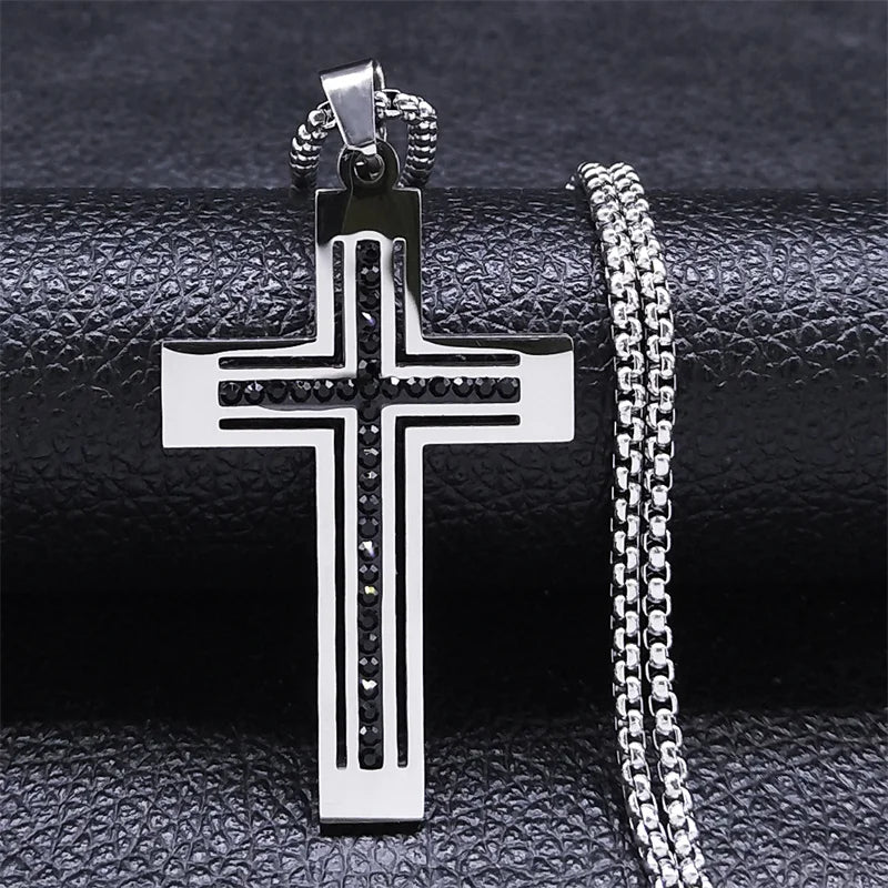 Silver cross pendant with chain on a textured black surface
