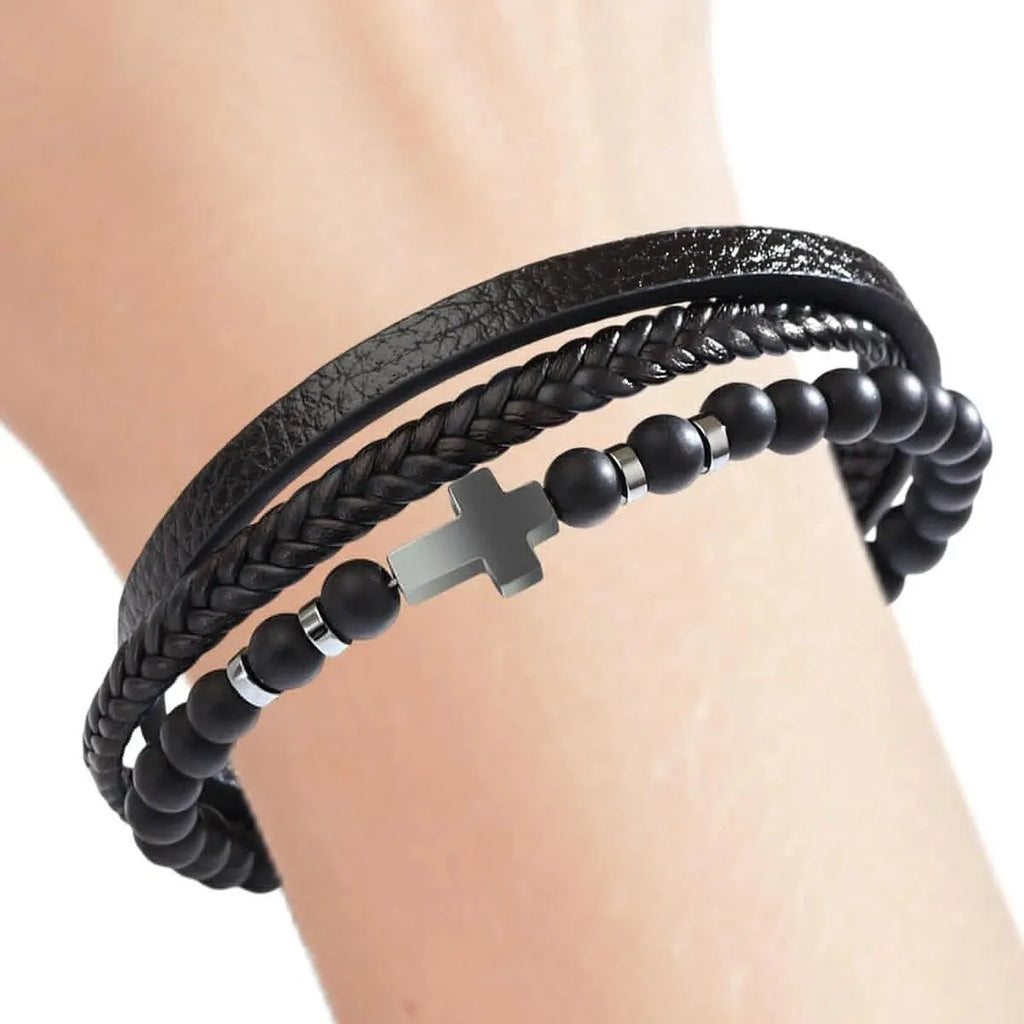 Black braided leather and beaded bracelet on a wrist against a neutral background