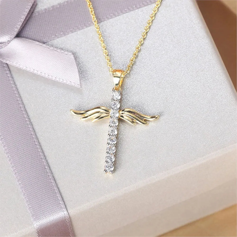 Gold cross necklace with diamond accents on a white box with purple ribbon