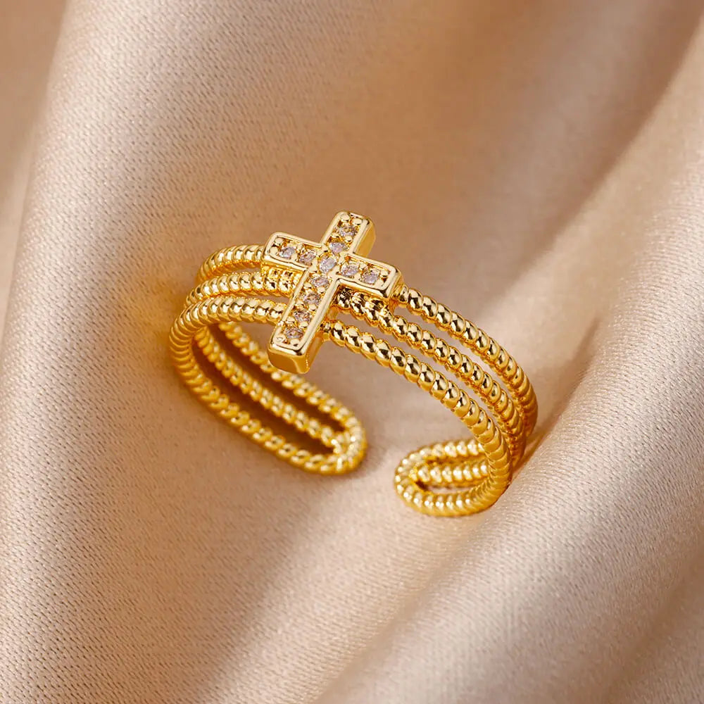 Gold ring with a cross design on a beige fabric background