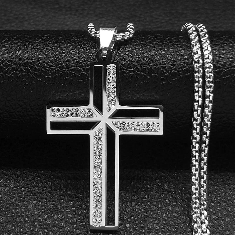 Silver cross pendant with chain on a textured black surface