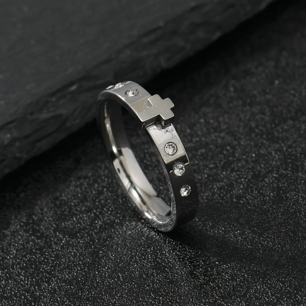 Silver ring with a cross design on a dark textured surface
