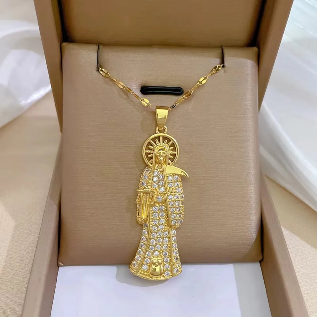 Gold pendant necklace with a religious figure design on a beige box.