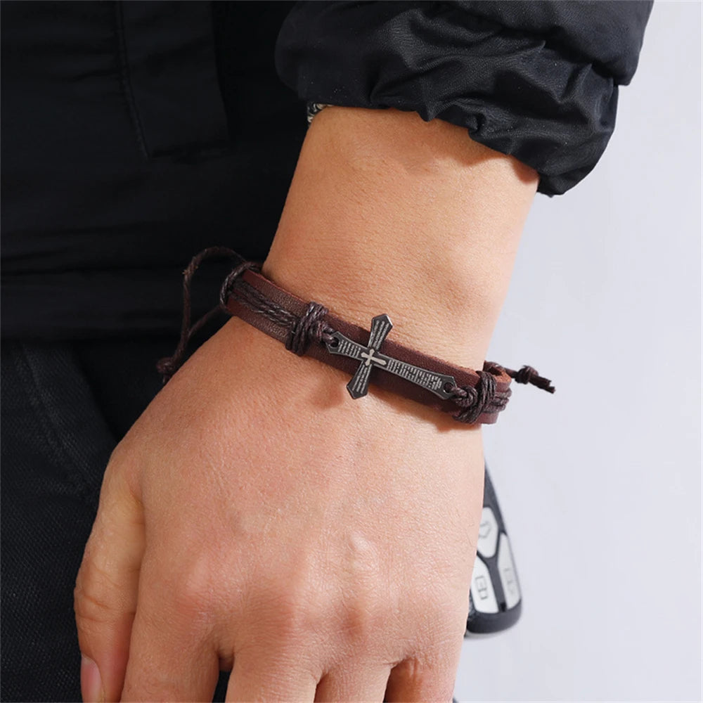Brown leather bracelet with a cross charm on a wrist against a neutral background