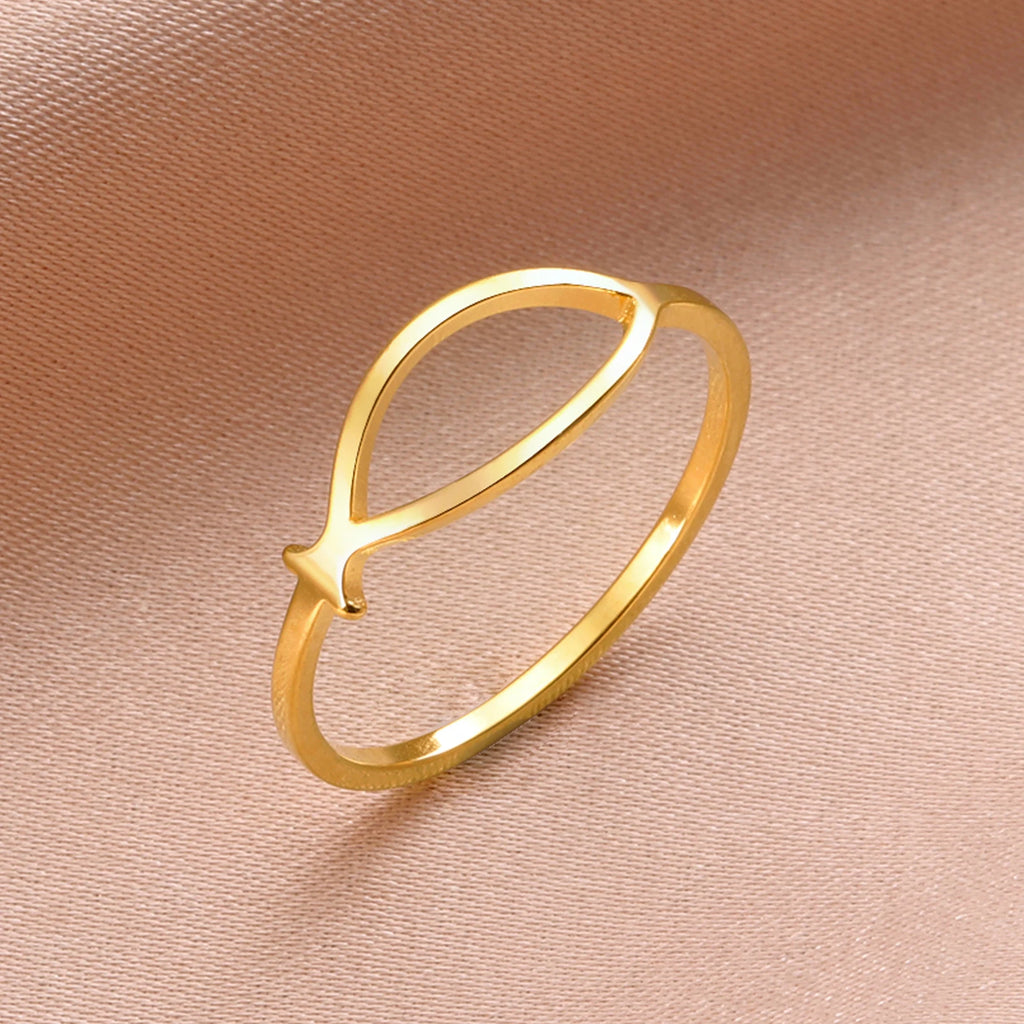 Gold ring with a fish design on a pink background