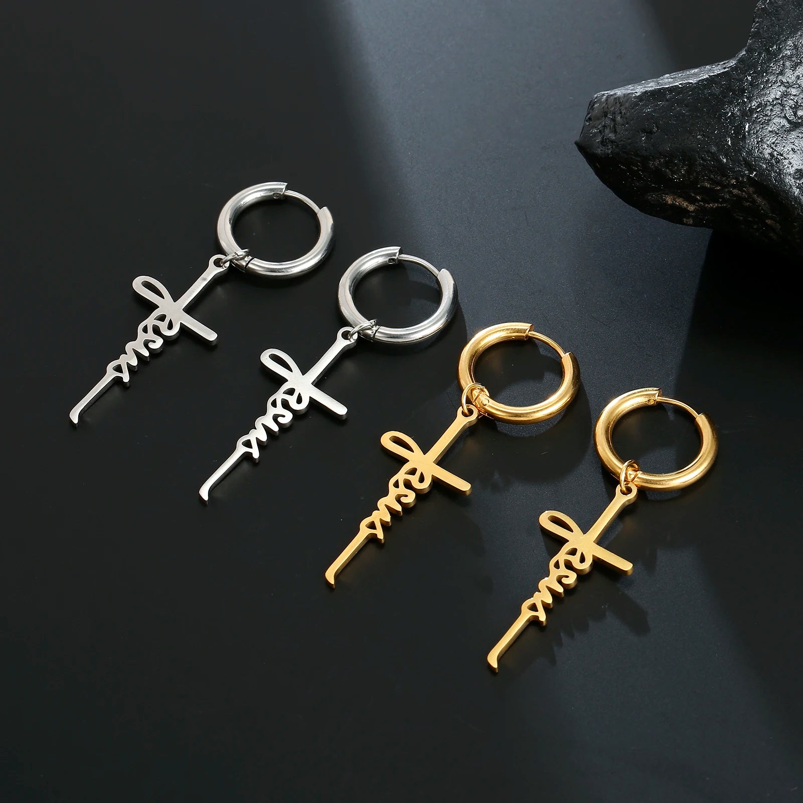 Pair of silver and gold hoop earrings with unique designs on a dark background