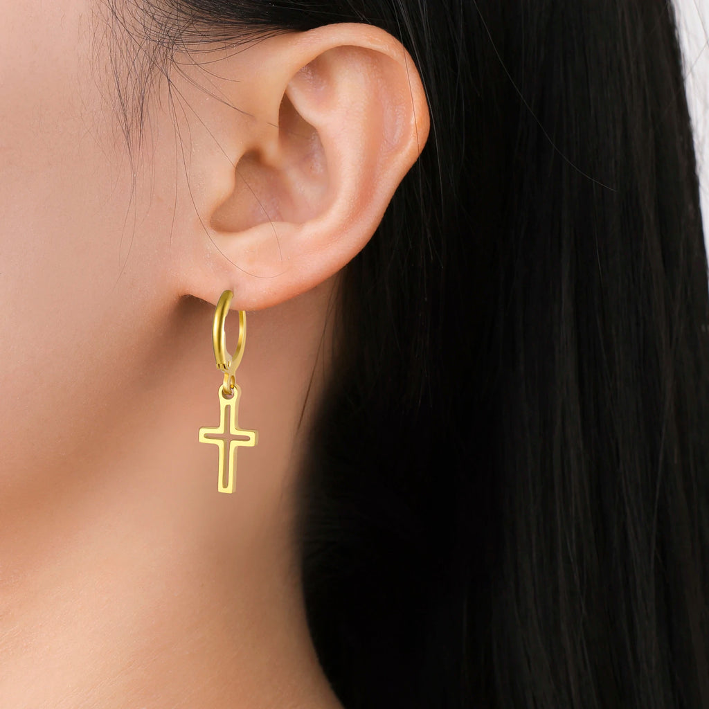 Gold hoop earring with a cross charm worn by a person