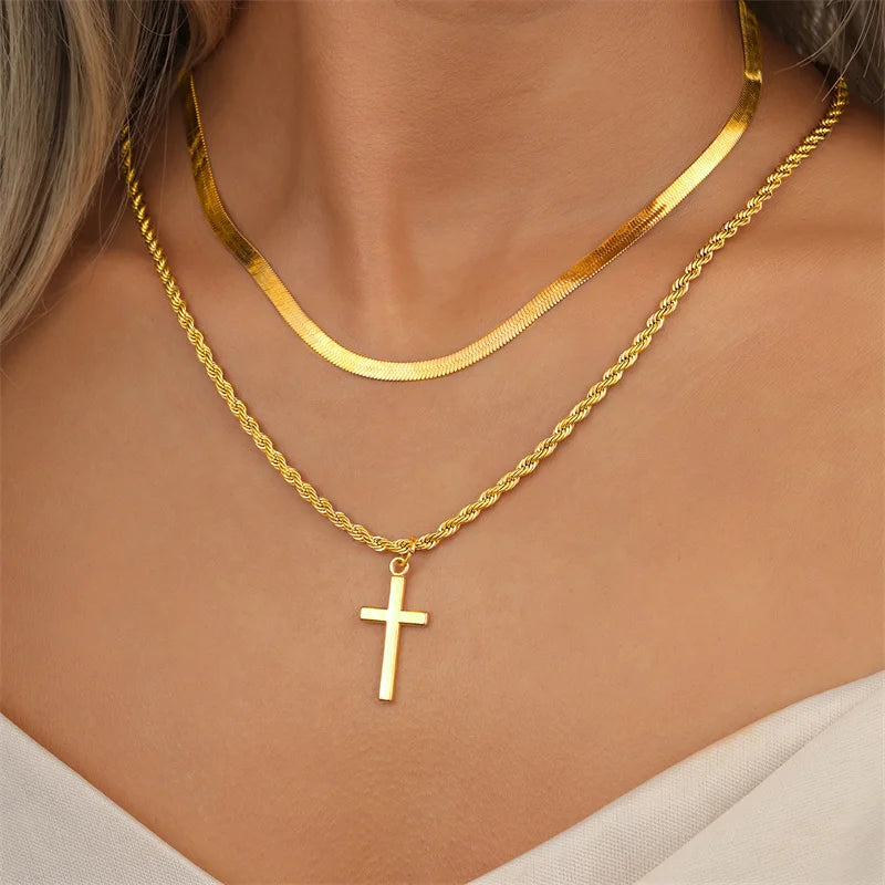 Gold necklaces with a cross pendant on a person's neck