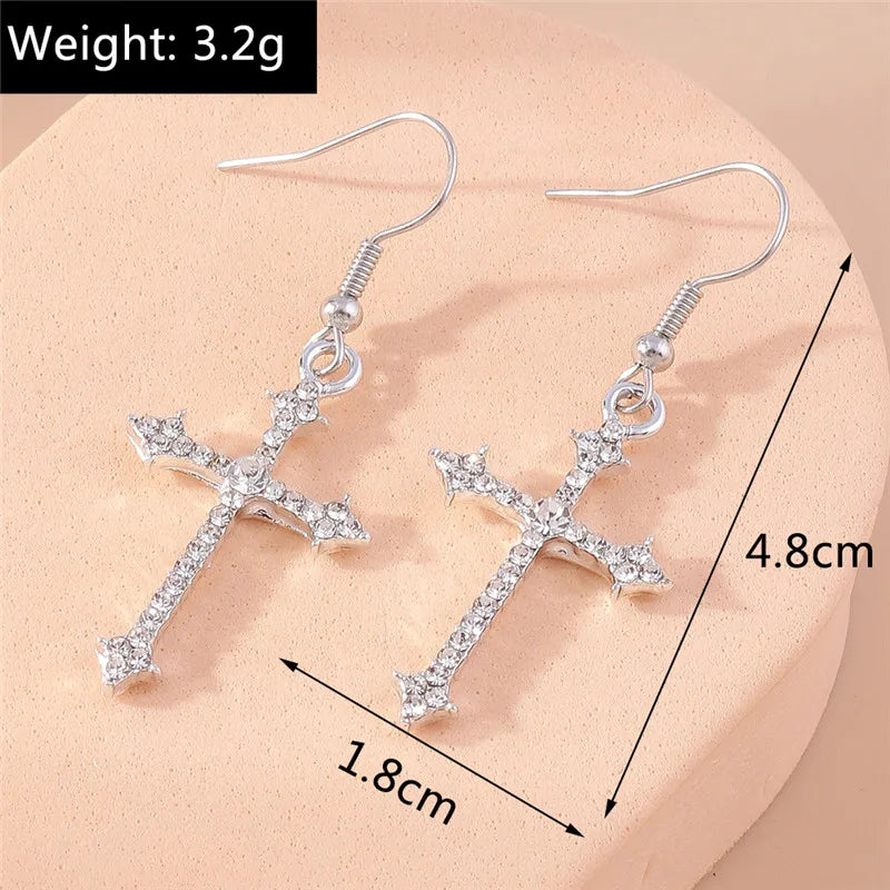 Silver cross earrings with measurements on a beige background
