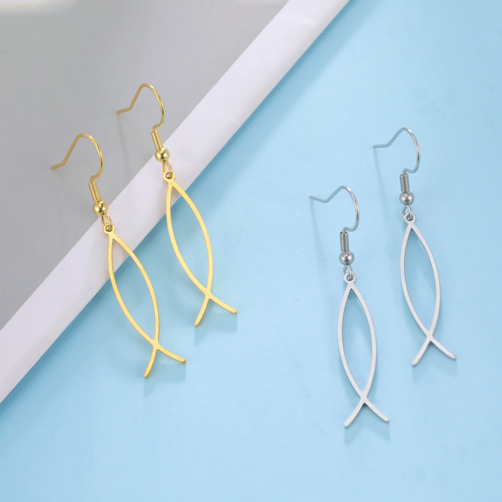 Gold and silver leaf-shaped earrings on a light blue and gray background