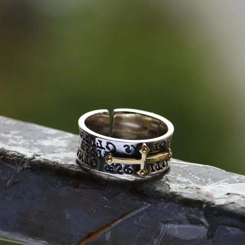 Silver and gold ring on a stone surface with a blurred green background