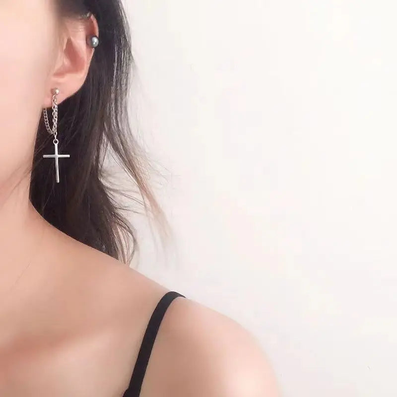 Silver cross earring on a model against a white background