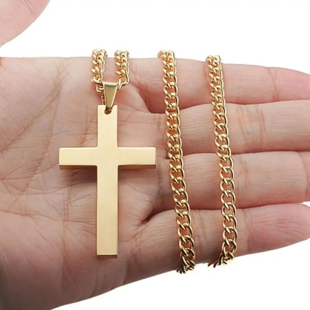 Gold cross pendant and chain held in a hand against a white background
