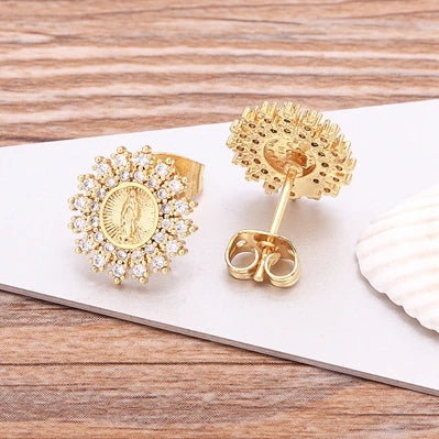 Gold earrings with intricate designs on a wooden surface