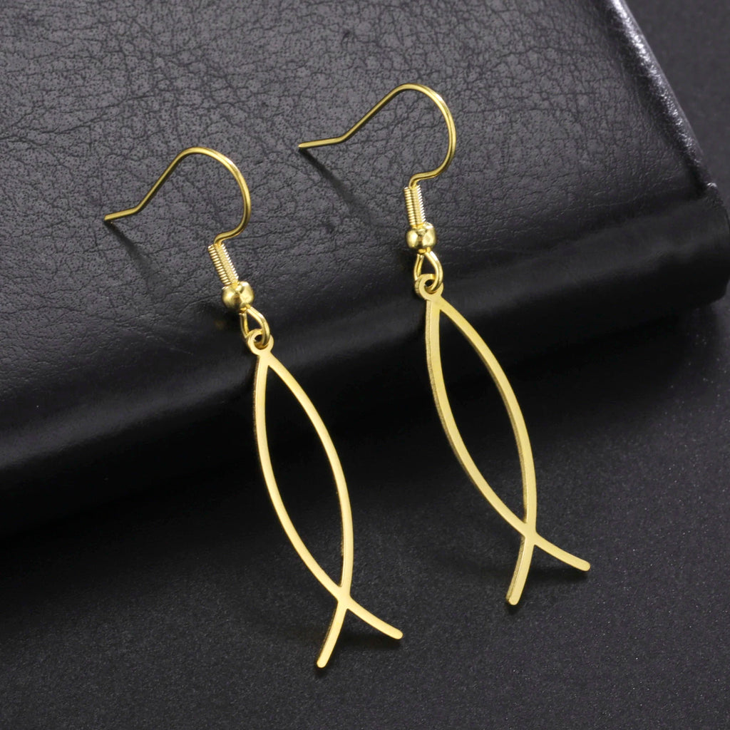Gold fish-shaped earrings on a dark textured surface