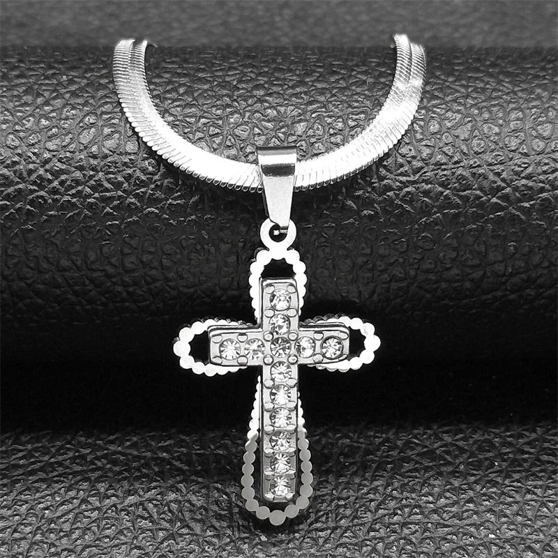 Silver cross pendant necklace on a textured black surface