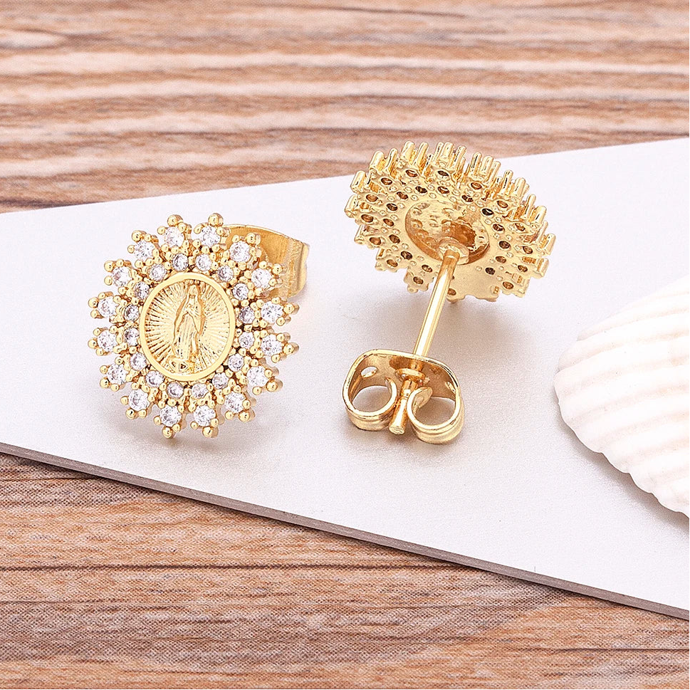 Gold earrings with intricate designs on a wooden surface