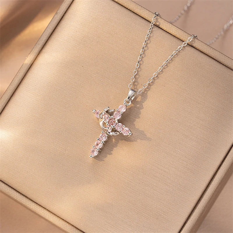 Silver necklace with a pink gemstone cross pendant on a beige background