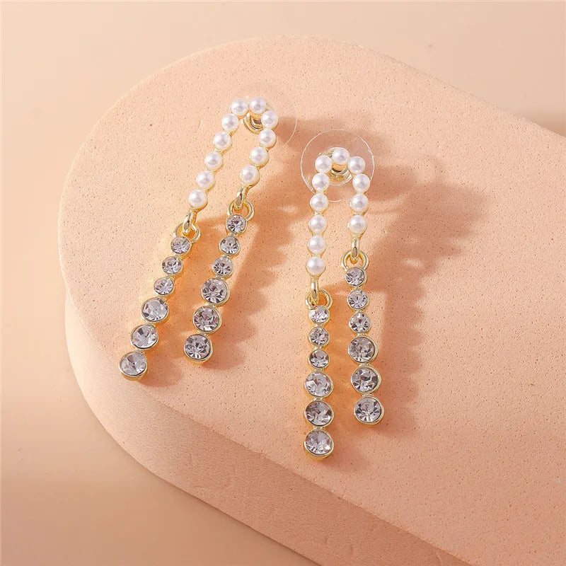 Pearl and crystal drop earrings on a beige background