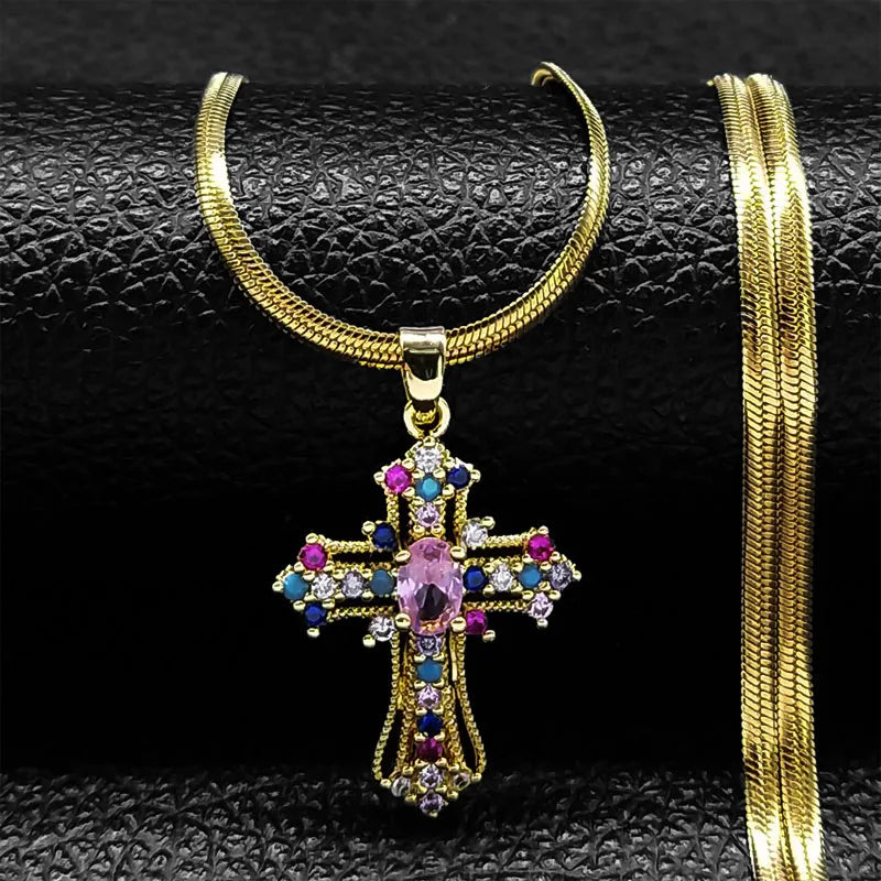 Gold cross necklace with colorful gemstones on a black textured surface