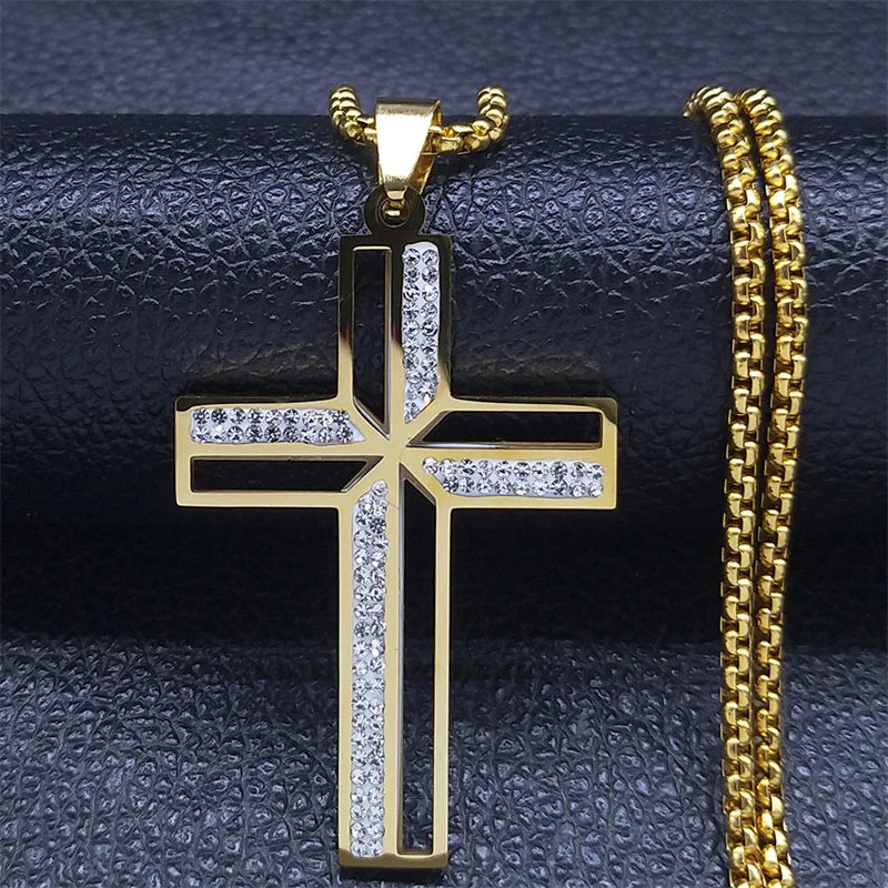 Gold cross pendant with clear stones on a gold chain against a dark textured background