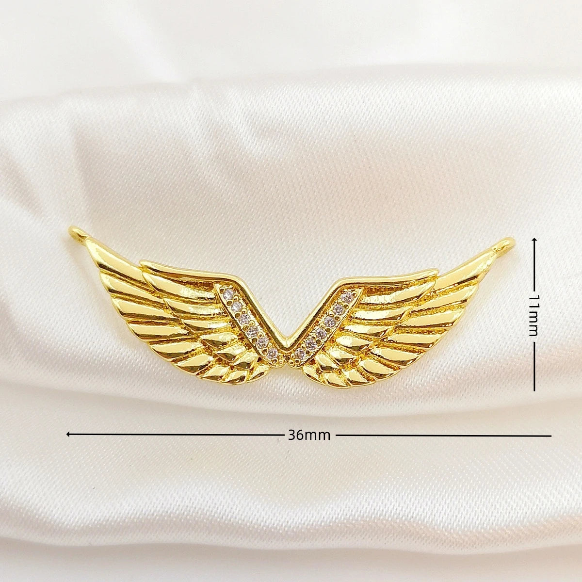 Gold wing-shaped brooch with measurements on a white background