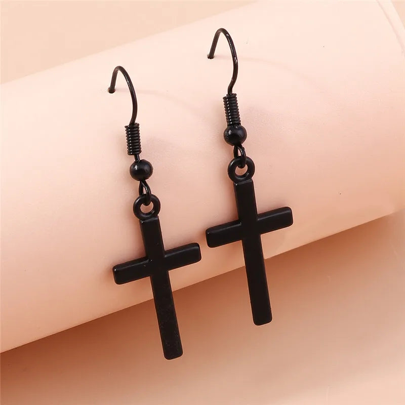 Black cross-shaped earrings on a beige background
