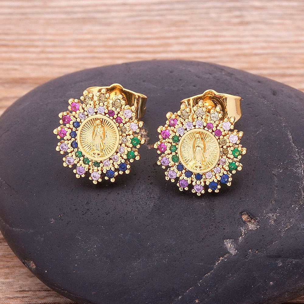 Gold earrings with colorful gemstones on a dark stone surface
