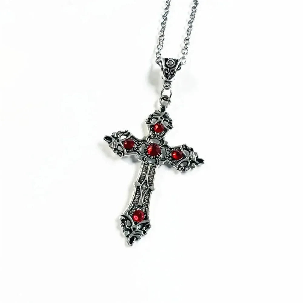 Silver cross pendant with red stones on a white background