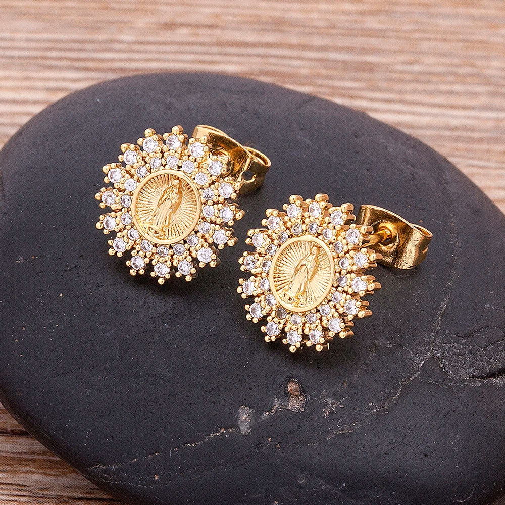 Gold earrings with gemstones on a black stone surface