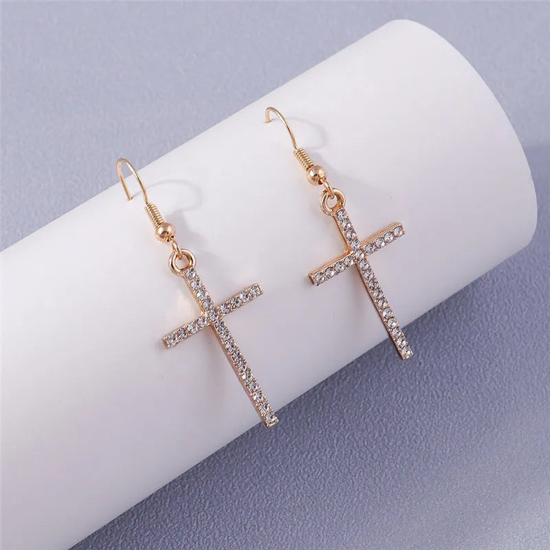Gold cross earrings with rhinestones on a white surface