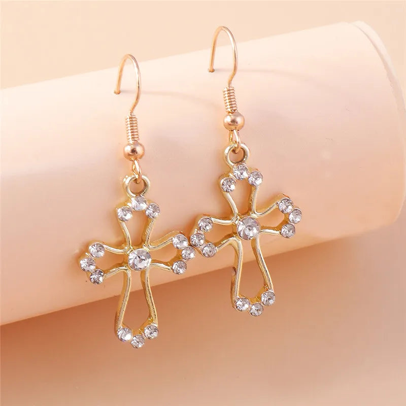 Gold floral earrings with clear stones on a beige background